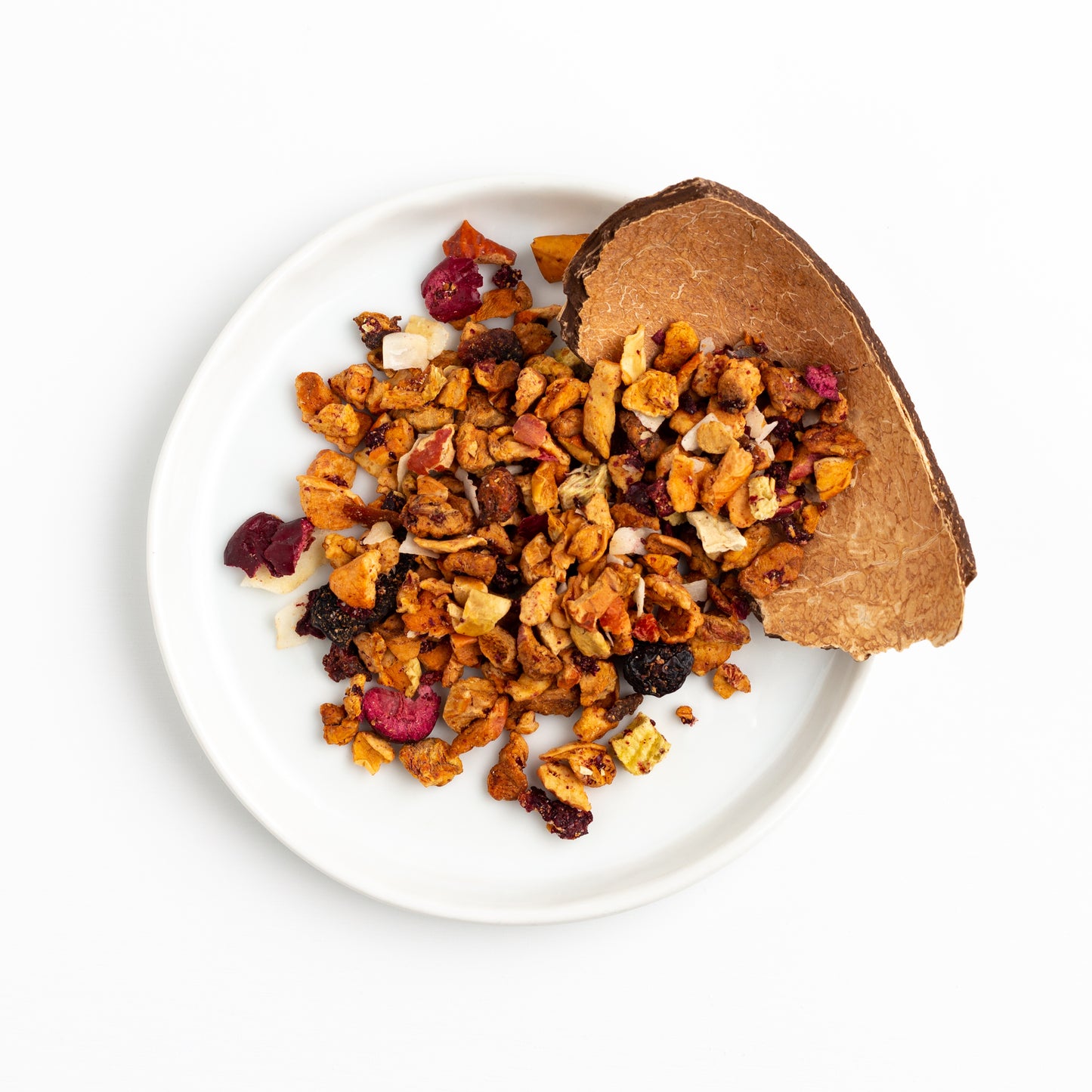 Pacific Paradise Herbal Tea shown from above as loose tea on a small white plate with a piece of coconut shell