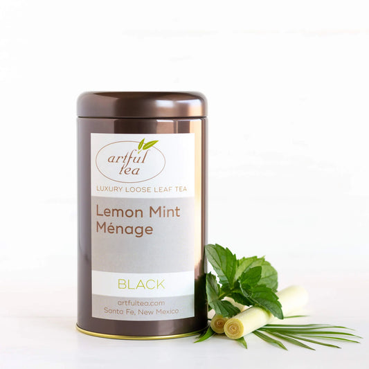 Lemon Mint Ménage Black Tea shown packaged in a brown tin with a sprig of mint and lemon grass next to it.