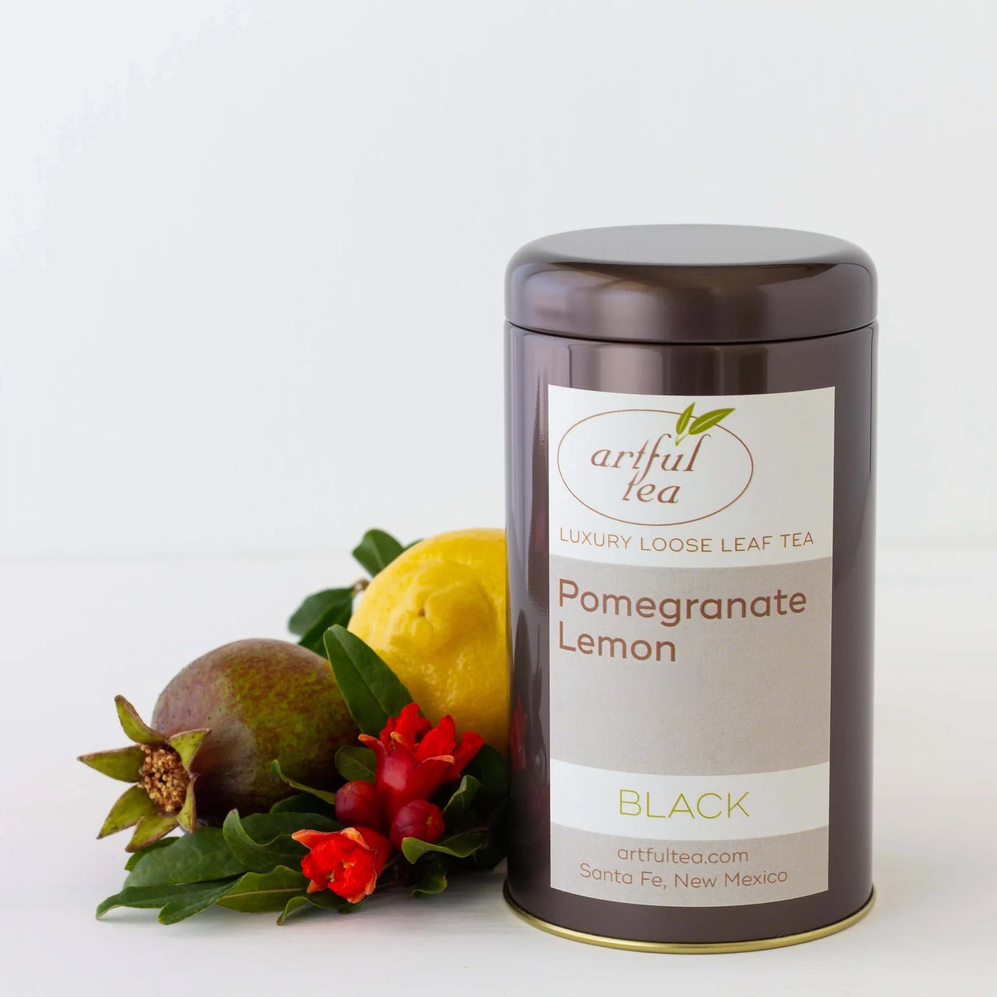 Pomegranate Lemon Black Tea shown packaged in a brown tin with ingredients next to it.