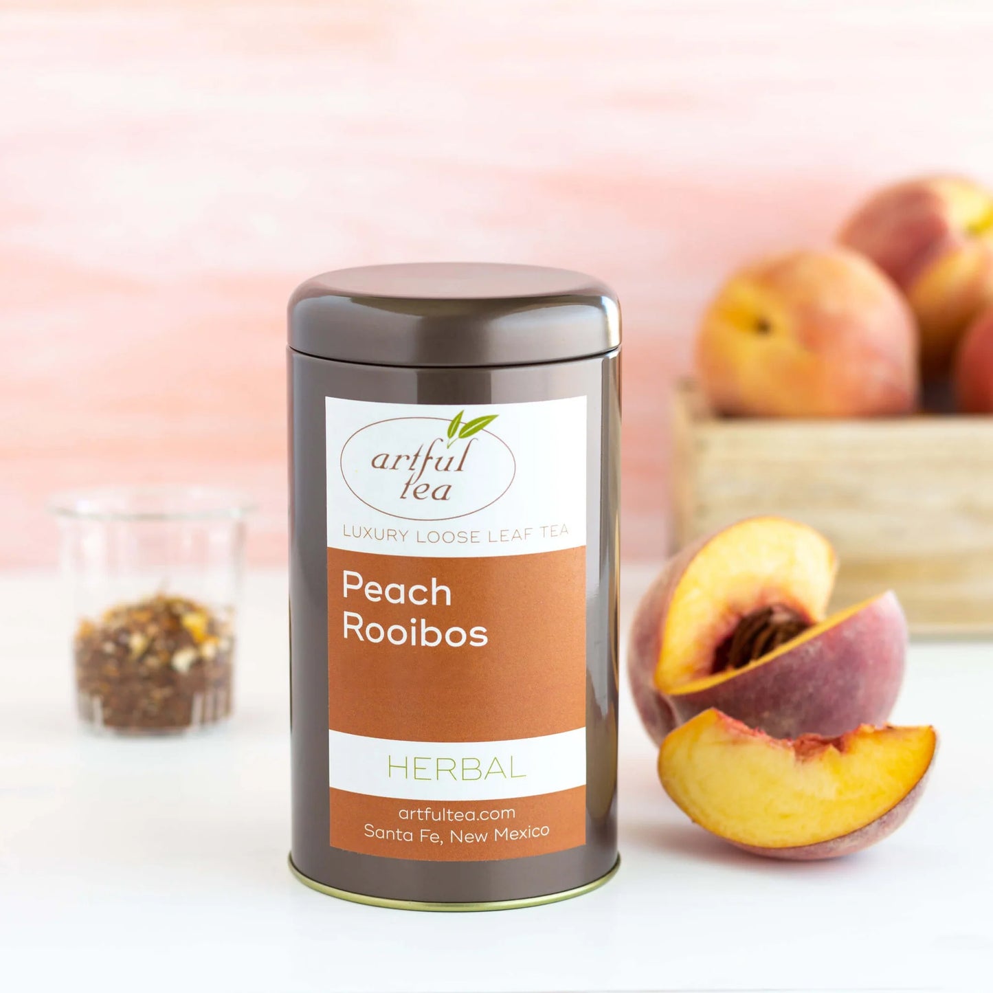 Peach Rooibos Herbal Tea shown packaged in a brown tin beside peaches.