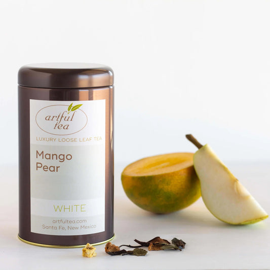 Mango Pear White Tea shown packaged in a brown tin with loose tea leaves next to it as well as a cut pear.