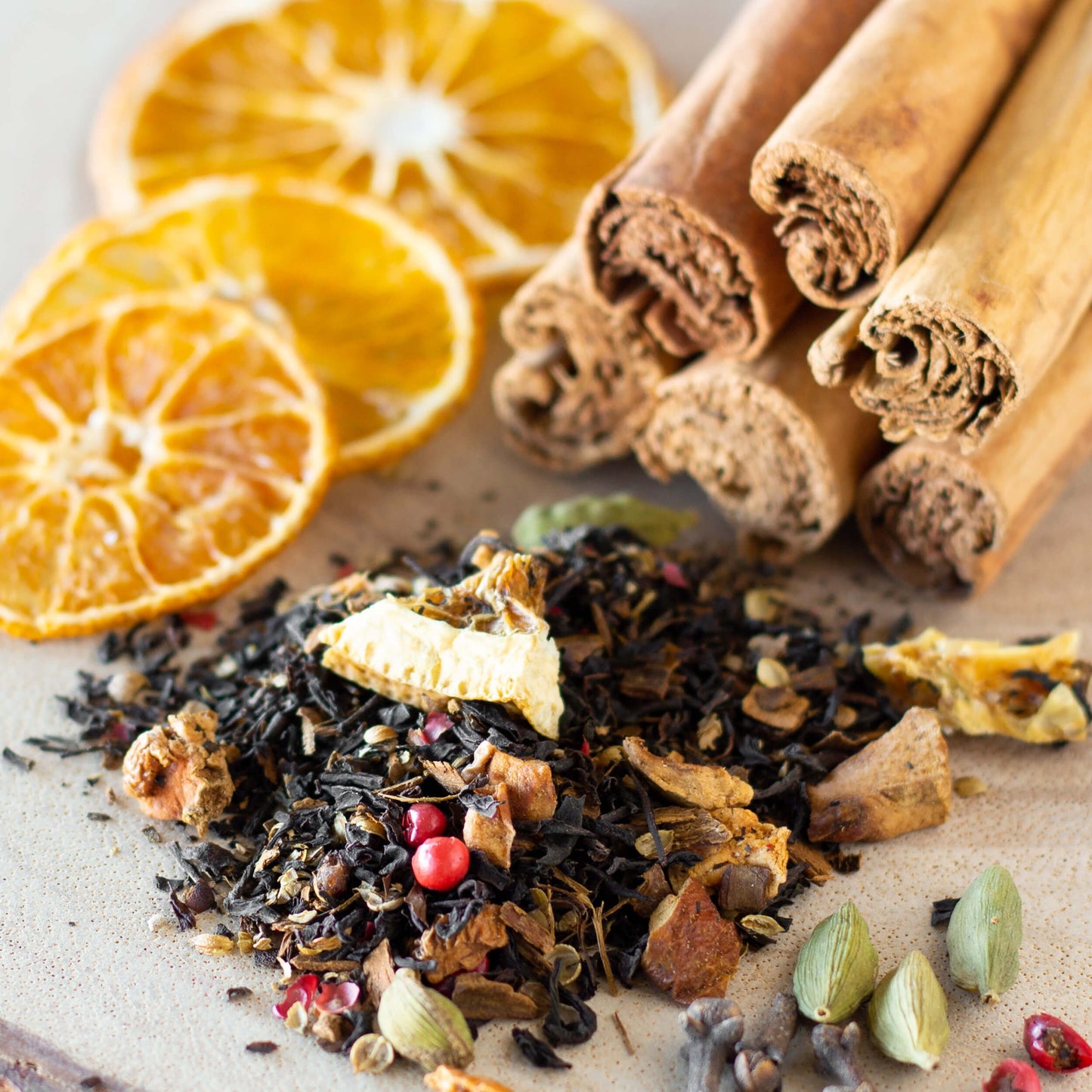 Solstice Spice loose tea leaves in a pile with the ingredients of oranges and cinnamon sticks surrounding it.