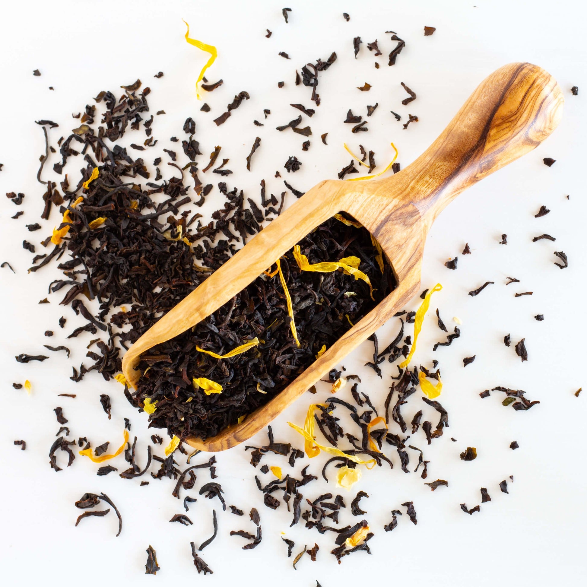 Vanilla Velvet loose black tea leaves shown spilling out of a large wooden scoop.
