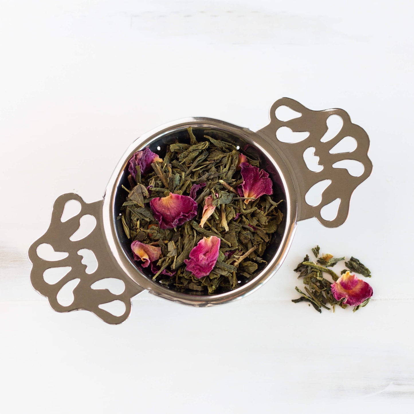 Cherry Rose Green Tea shown above as loose leaf tea in a strainer.