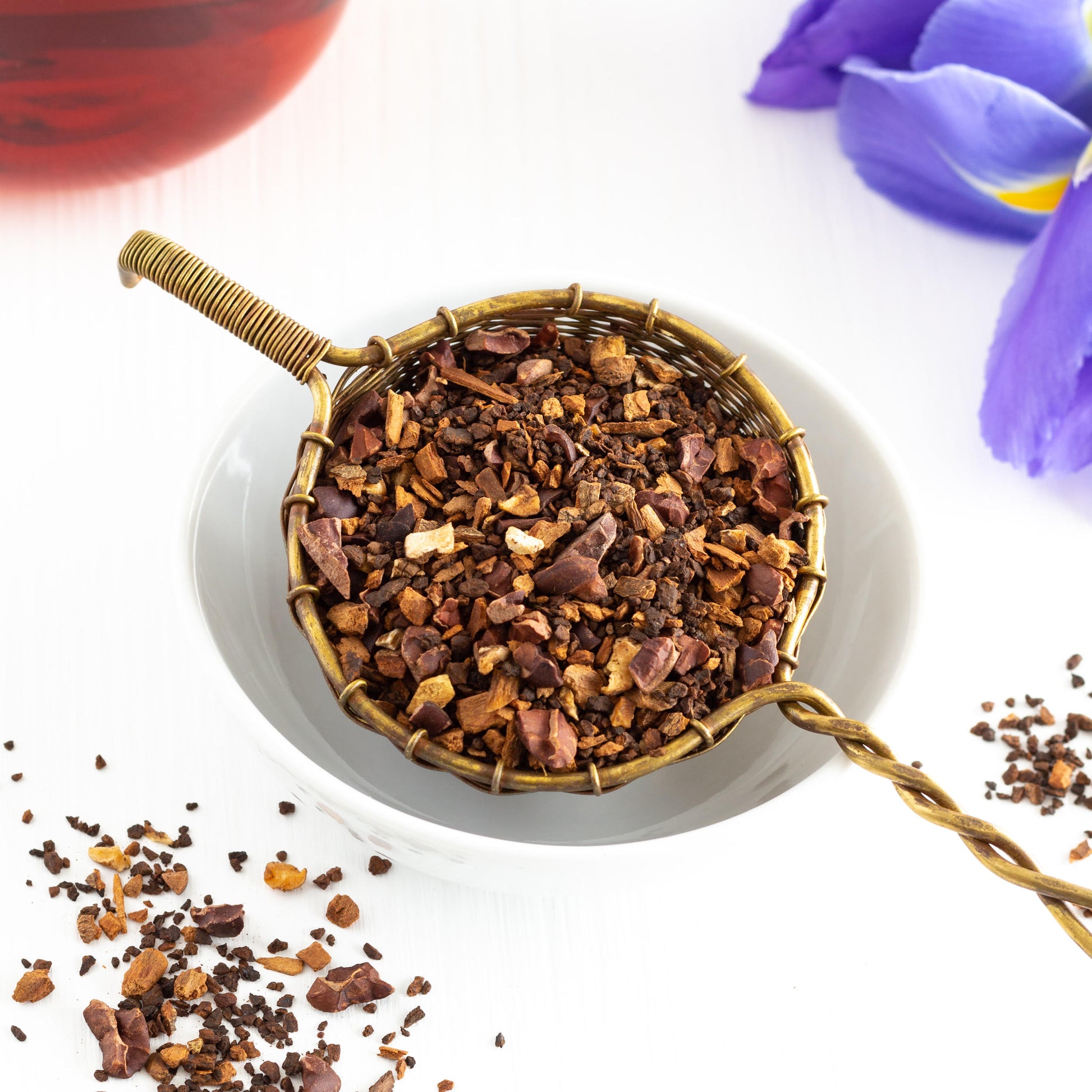 Chicory Chocolate Herbal Tea shown as loose tea in a golden basket above a white bowl.
