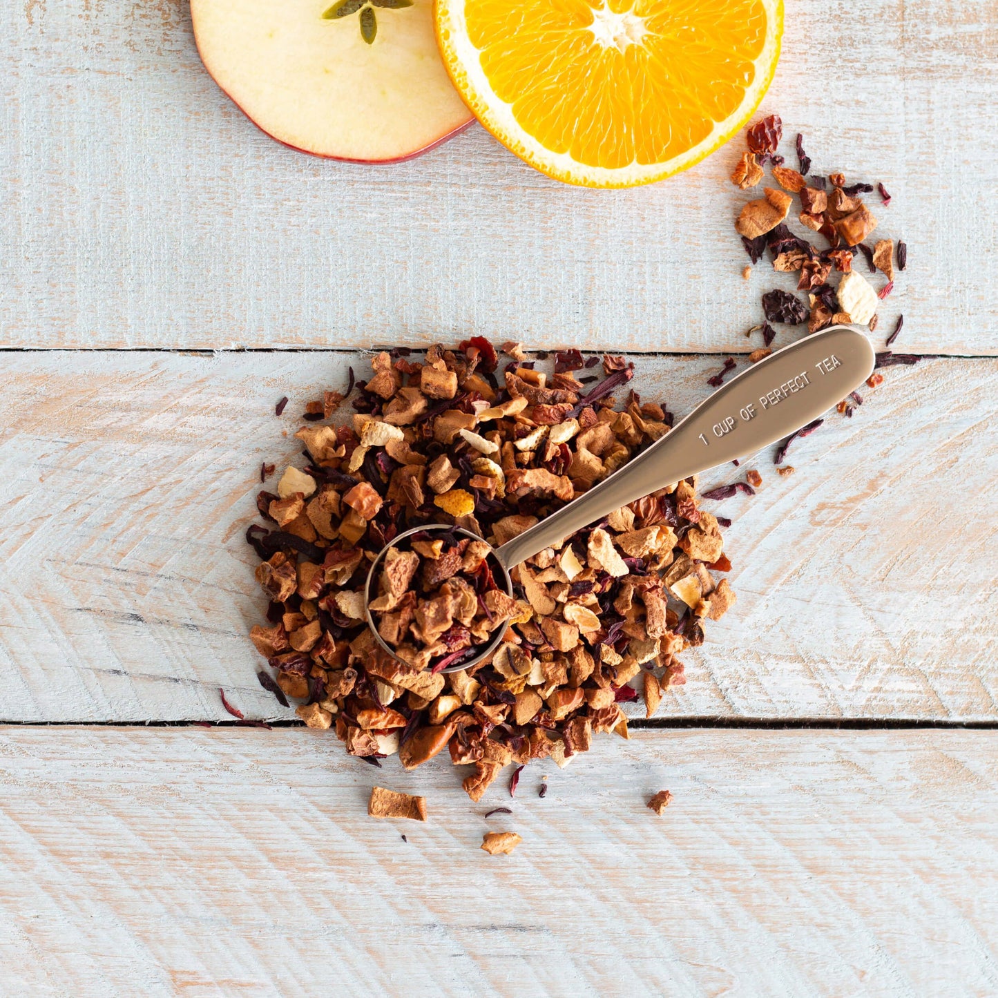 Apples to Oranges Herbal Tea shown from above as loose leaf tea in a circular pile with a teaspoon on top of it.