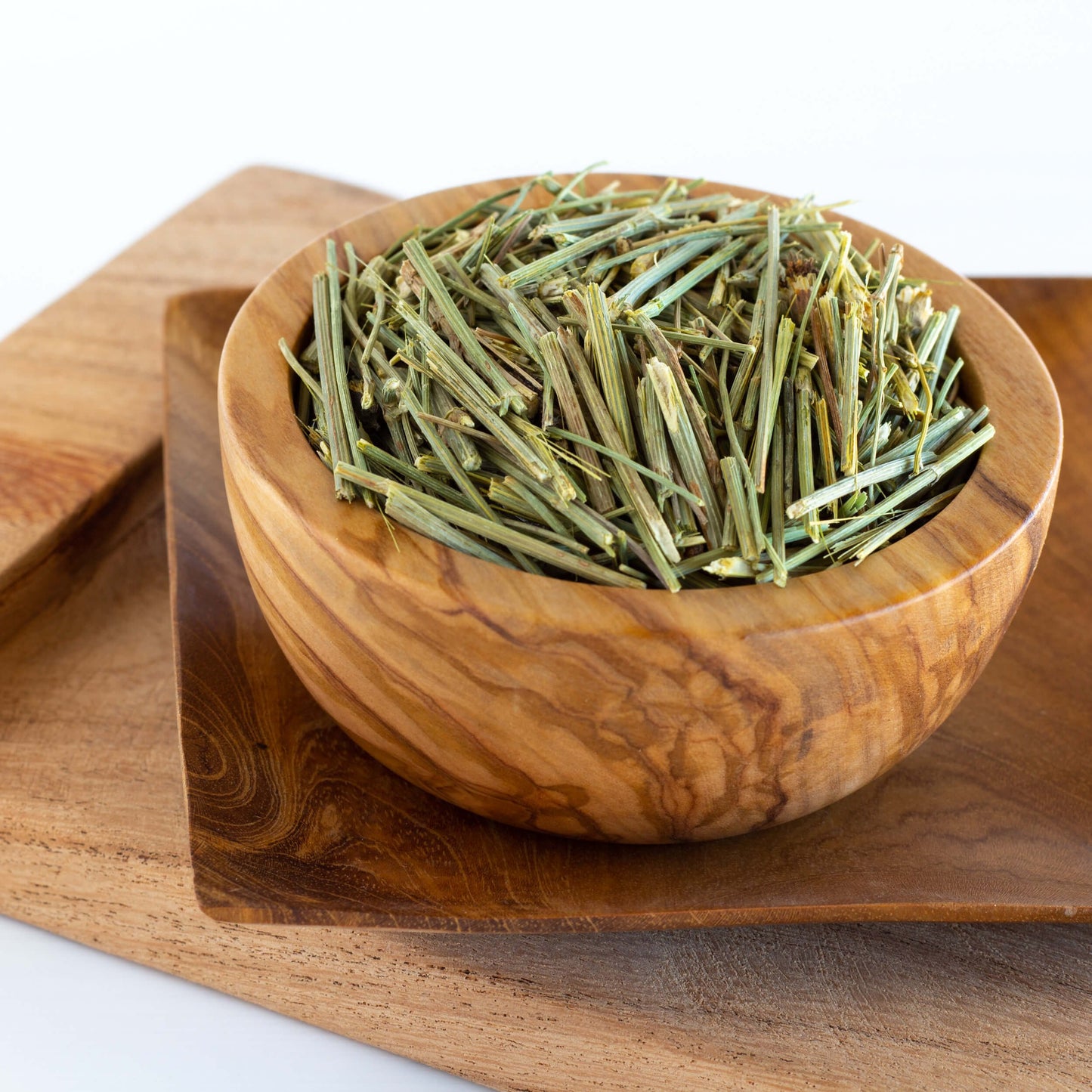 Cota Navajo Herbal Tea shown as loose tea in a wooden bowl on top of wooden trays.