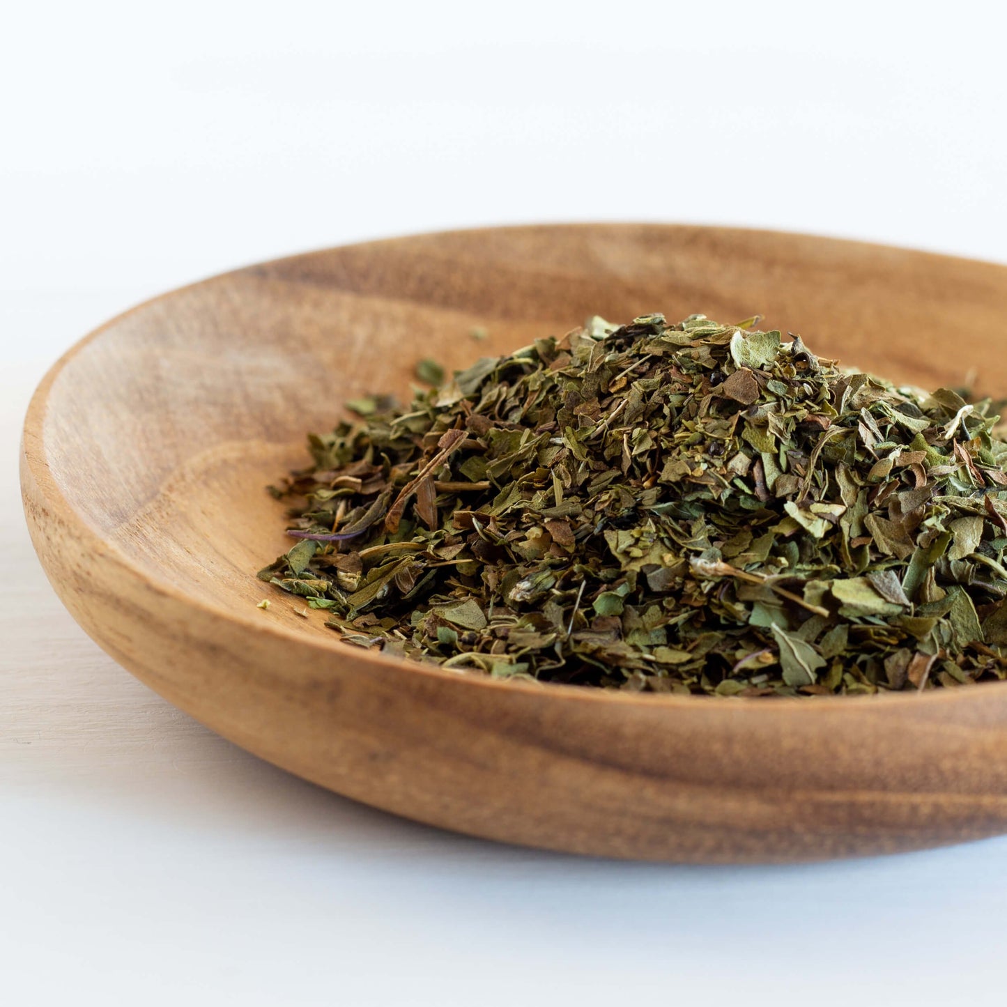 Peppermint Herbal Tea shown as loose leaf tea in a wooden bowl.