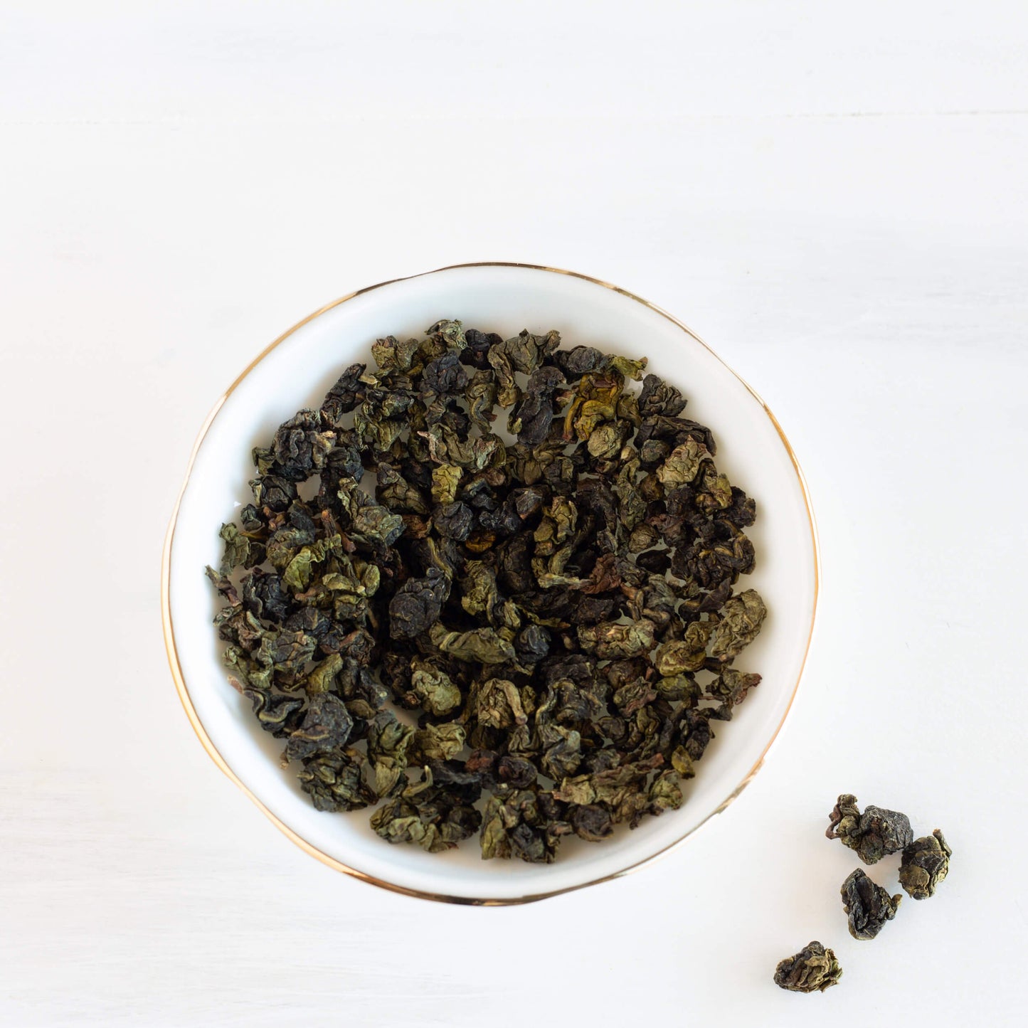 Fine Ti Kuan Yin Oolong Tea shown from above as loose leaf tea inside of a white bowl.