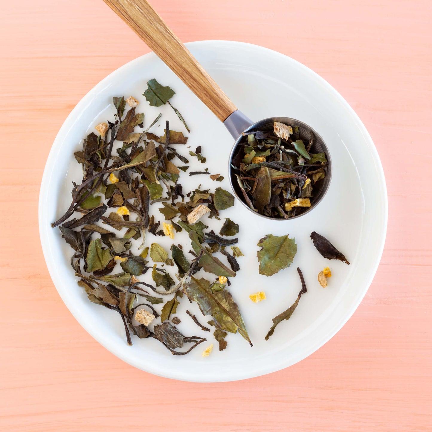 Peachy Keen White Tea shown as loose leaf tea in a scoop on a white plate with more loose leaf tea.