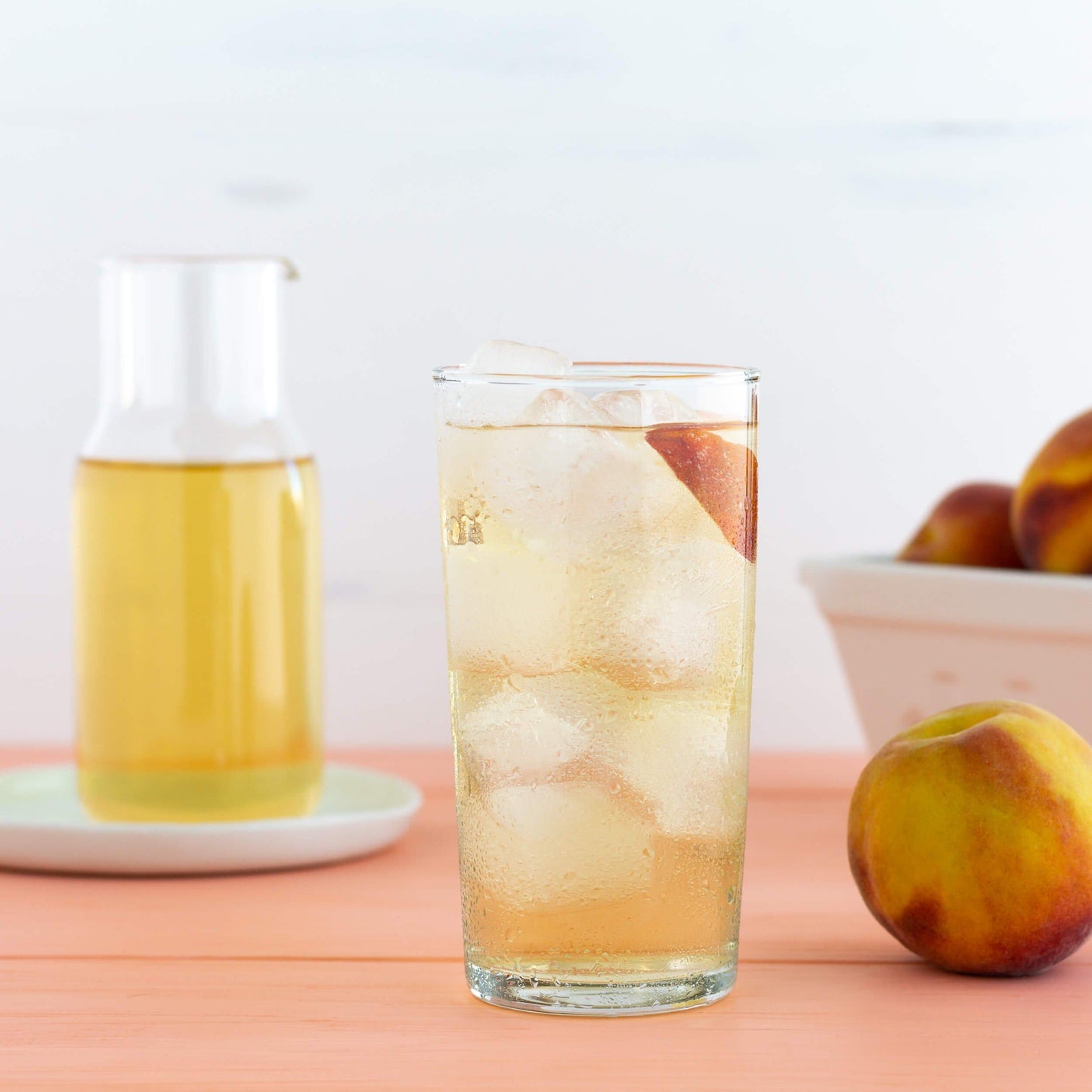 Peachy Keen Organic White Tea prepared as iced tea, shown with carafe of brewed tea and peaches
