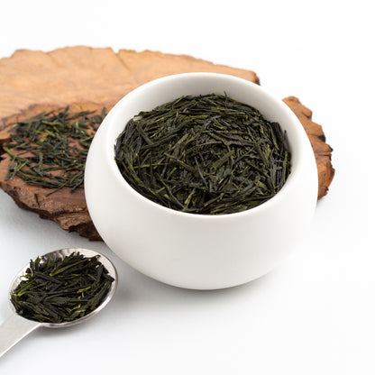 Sencha Sayama Kaori Green Tea shown as deep green loose tea leaves in a small white cup, with a spoon and loose leaves nearby