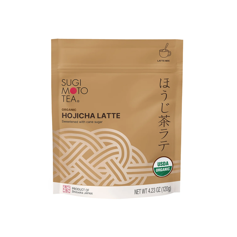A stand-up pouch of Organic Hojicha Latte, featuring a warm tan background with a white geometric knot design, black and red text, and a USDA Organic seal.