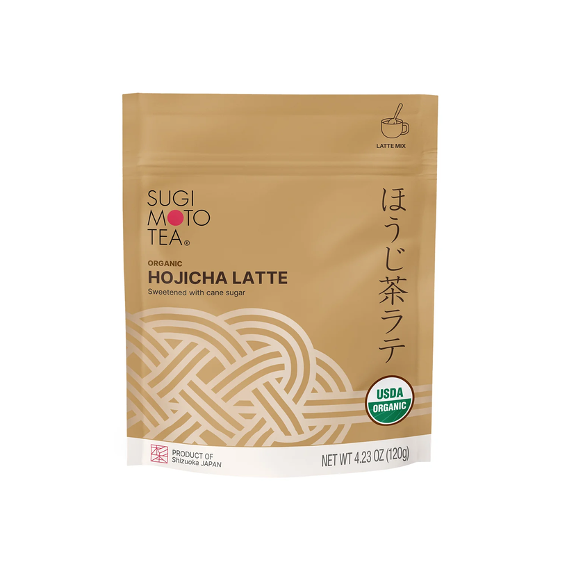 A stand-up pouch of Organic Hojicha Latte, featuring a warm tan background with a white geometric knot design, black and red text, and a USDA Organic seal.
