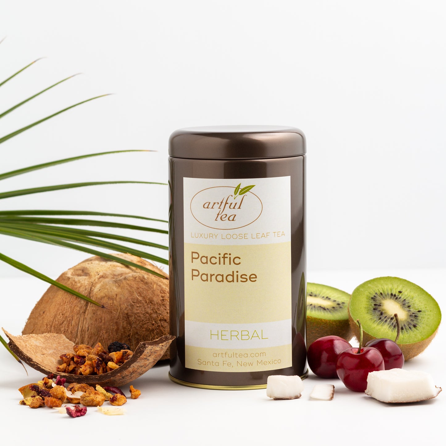 Pacific Paradise Herbal Tea shown packaged in a brown tin, surrounded by fresh kiwi, cherries and coconut