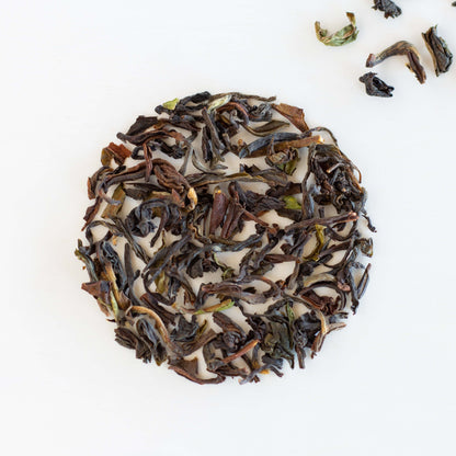 Organic Darjeeling Black Tea shown from above as loose tea leaves in a circle with a few leaves scattered in upper right corner