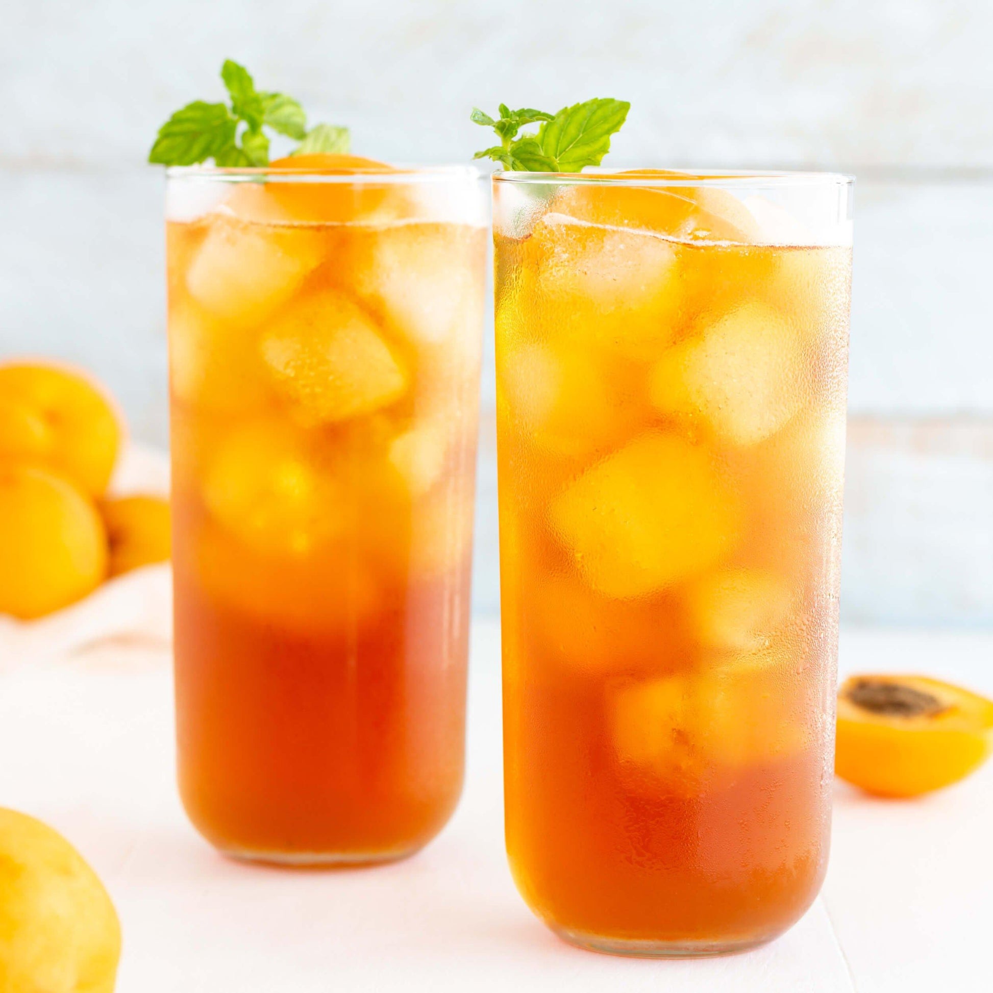 Apricot Brandy Organic Black Tea shown as iced tea in two tall glasses with mint sprigs