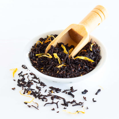 Apricot Brandy Organic Black Tea shown as loose tea leaves in a small white bowl with a wooden scoop