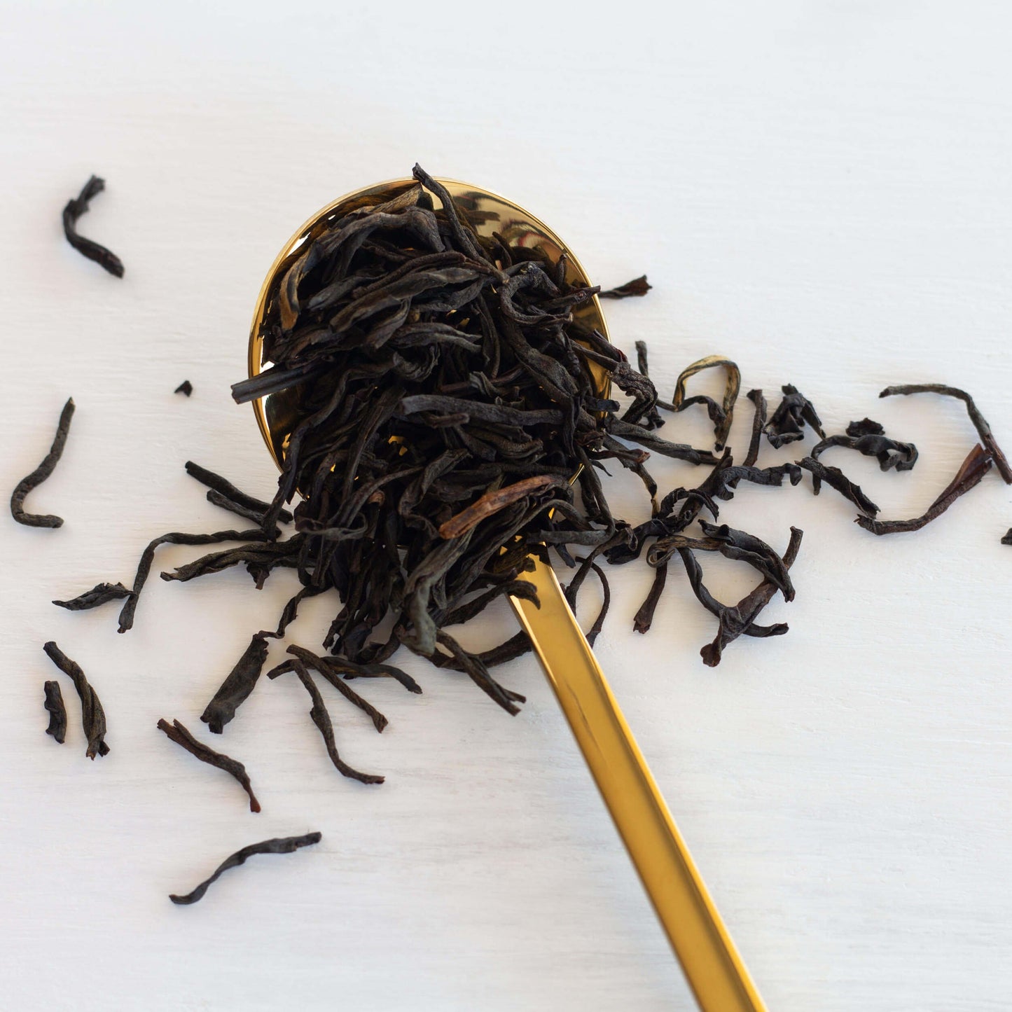 Earl Grey Français Black Tea shown from above as loose tea leaves overflowing a gold spoon.