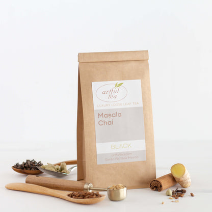 Masala Chai Black Tea shown packaged in a kraft bag with four spoons full of spices nearby