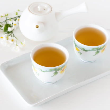 Jasmine Yin Cloud Organic Green Tea shown as brewed tea in two small white teacups with green and yellow floral design, displayed on a white rectangular tray with a white kyusu teapot in the background