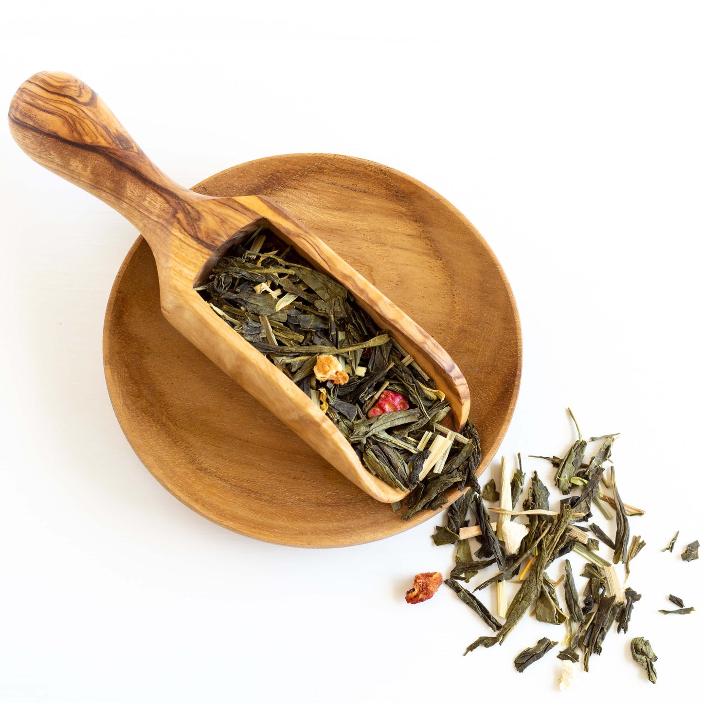 Sunrise Melody Organic Green Tea shown from above as loose tea leaves in a wooden scoop on a small wooden dish
