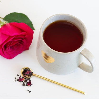 White mug with gold heart, black tea, and roses