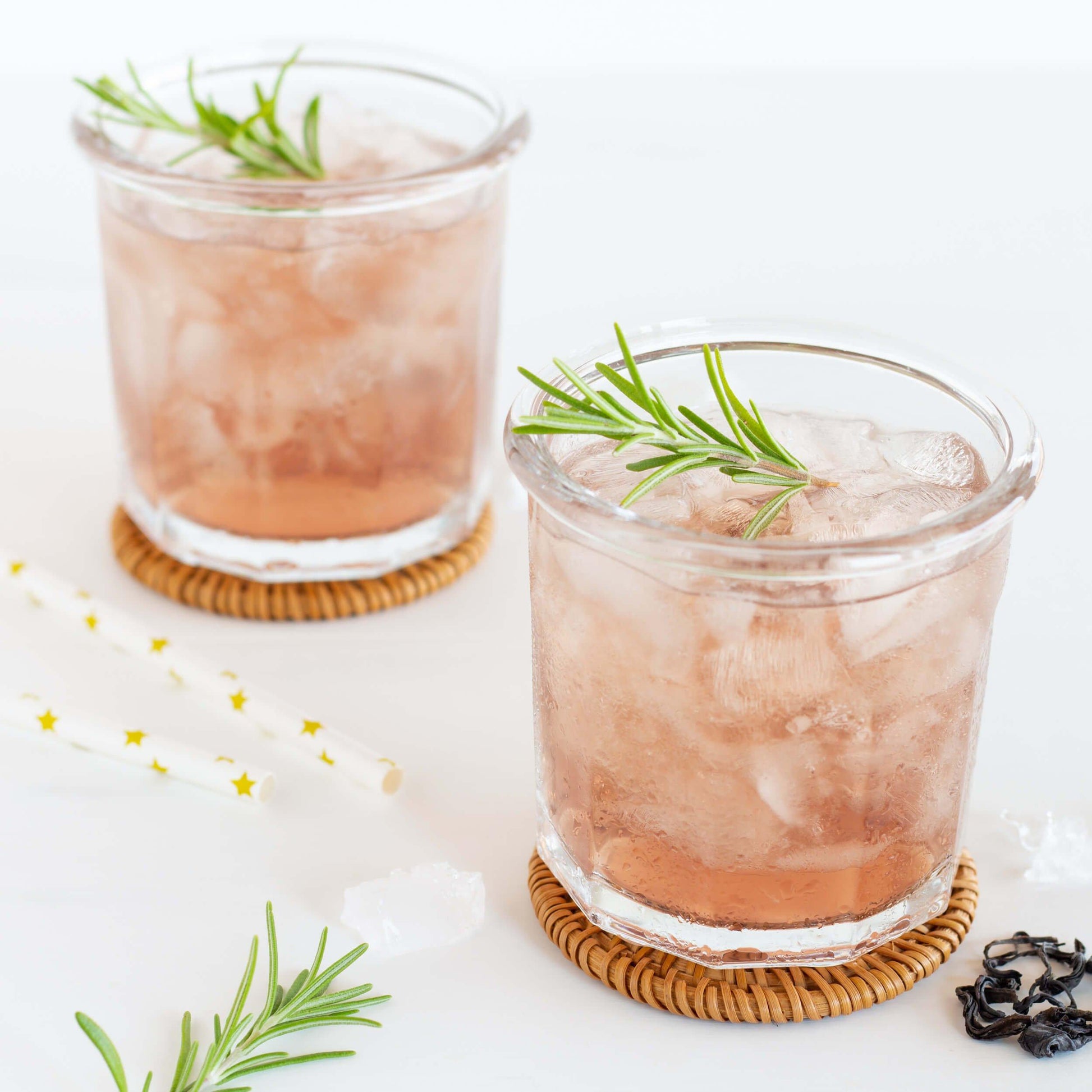 Kenyan Purple Leaf Tea shown as iced tea in two short glasses with sprigs of rosemary as a garnish
